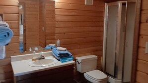 A wooden cabin bathroom with a sink, mirror, and toilet.
