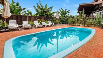 Una piscina al aire libre, sombrillas, tumbonas