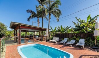 Una piscina al aire libre, sombrillas, sillones reclinables de piscina