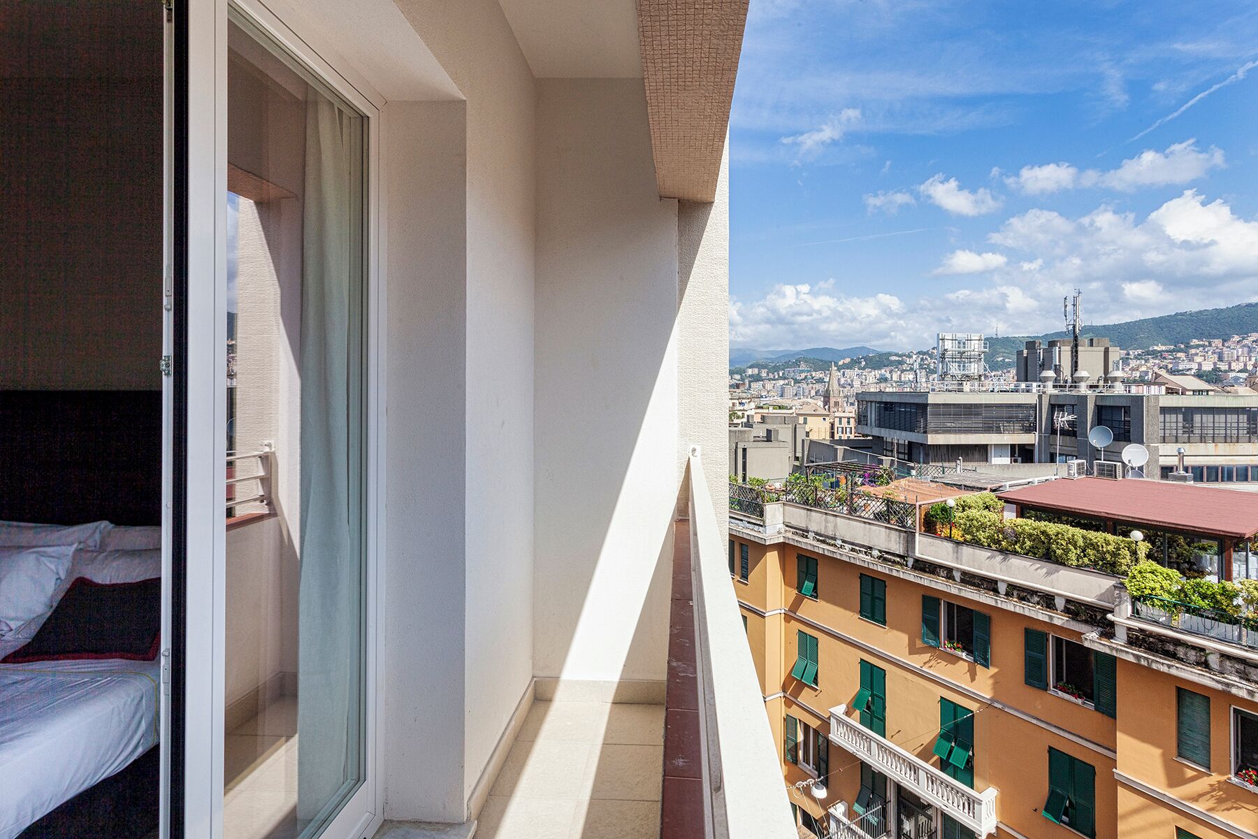 Un balcon avec vue sur la ville, un lit et une fenêtre avec des rideaux.
