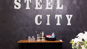 Een bar met een donker, honingraatvormig patroon op de muur, een houten bar en een bord met de tekst 'STEEL CITY'.