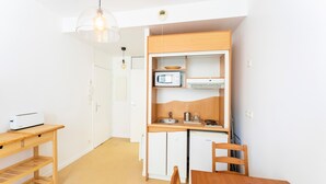 A compact kitchen with a microwave, sink, and a small refrigerator. There is a wooden table and chairs in the dining area. - Studio Apartment 'Charmant Studio Centre Bayonne' (Bayonne)