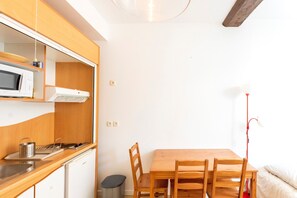 Une cuisine de taille réduite, équipée d’un four à micro-ondes, d’un évier et de meubles de rangement en bois.