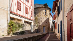 A narrow street with traditional half-timbered buildings, a stone wall, and a small gate. - Studio Apartment 'Charmant Studio Centre Bayonne' (Bayonne)