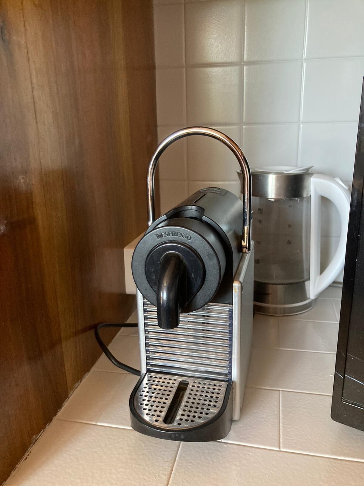 A kitchen with a coffee maker, a kettle, and a mug on the counter.