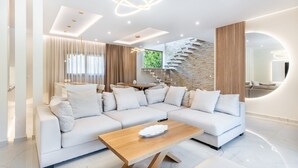 Una sala de estar moderna con un sofá seccional, una mesa de centro de madera, una escalera y un espejo grande.