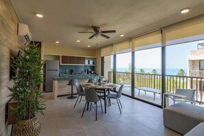 Une cuisine moderne avec un coin repas et un balcon offrant une vue sur l’océan.