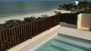 A pool with clear water, a wooden fence, and a view of the beach and ocean.