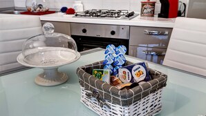 A kitchen with a glass cake stand, a wicker basket with food items, and a gas stove. - 'Loano Relax' Apartment with Private Terrace and Garden (Loano)