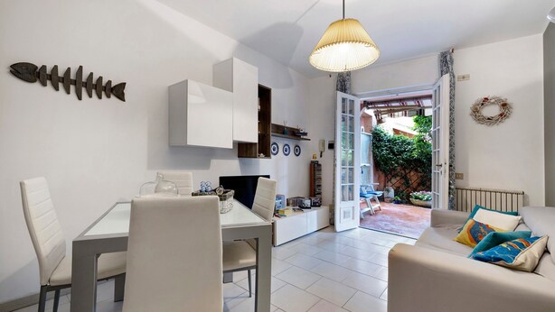 A modern interior with a dining area, sofa, and a view to an outdoor patio. - 'Loano Relax' Apartment with Private Terrace and Garden (Loano)
