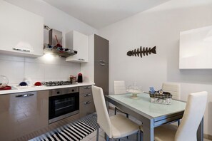 Una cucina moderna con mobili bianchi, un piano cottura a gas e un tavolo con sedie.