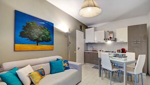 A modern living room with a sofa, a dining table with chairs, and a kitchen area with cabinets and appliances. - 'Loano Relax' Apartment with Private Terrace and Garden (Loano)