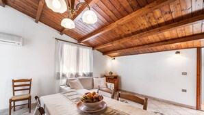 Una habitación con techo de madera, una mesa de comedor con frutero, un sofá y una silla.