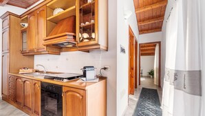 Una cocina con armarios de madera, horno empotrado y una encimera con cafetera.