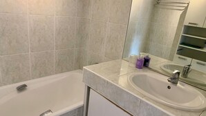 Een badkamer met een bad, wastafel en spiegel.
