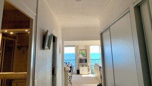 Een gang met uitzicht op zee, een plafondlamp en een deur links.
