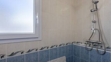 A bathroom with a shower, a window, and decorative tiles.