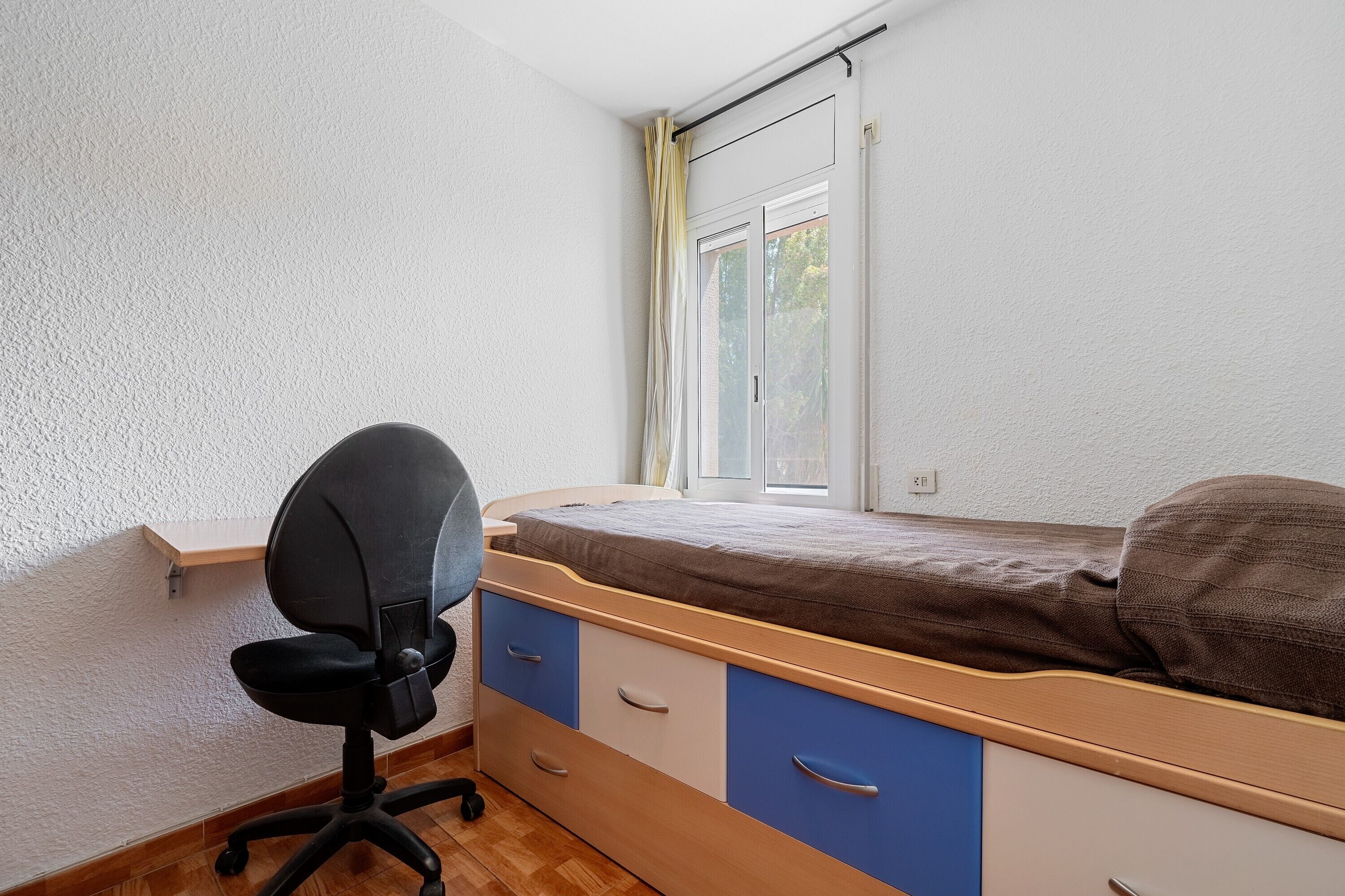 Ein Schlafzimmer mit Bett, Schreibtisch und Stuhl.