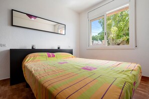 Une chambre à coucher avec un lit, une fenêtre donnant sur des arbres et un miroir au mur.