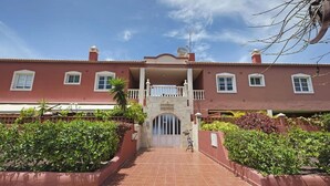 A two-story building with a red facade, a central entrance with a gate, and a balcony on the upper floor. - 2-bed House Sleeps 4 With Free Parking (Puerto de la Cruz)