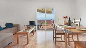 Una sala de estar con sofá, televisor y un comedor con mesa y sillas.
