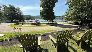 Ein Park mit grünen Stühlen und einem roten Lastwagen, ein See und Bäume im Hintergrund.