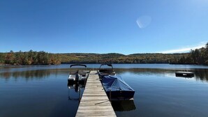 A wooden dock extending into calm water with a clear sky above. - Lakeside Cabin 6 with Kitchen (Holderness)