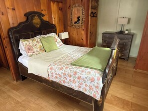 A wooden-paneled bedroom with a bed, a dresser, and a mirror.