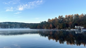 A calm lake with a dock and a house on the right. - Lakeside Cabin 7 with Kitchen (Holderness)
