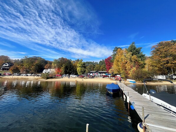 A lakeside view with a dock, boats, and a sandy beach area.