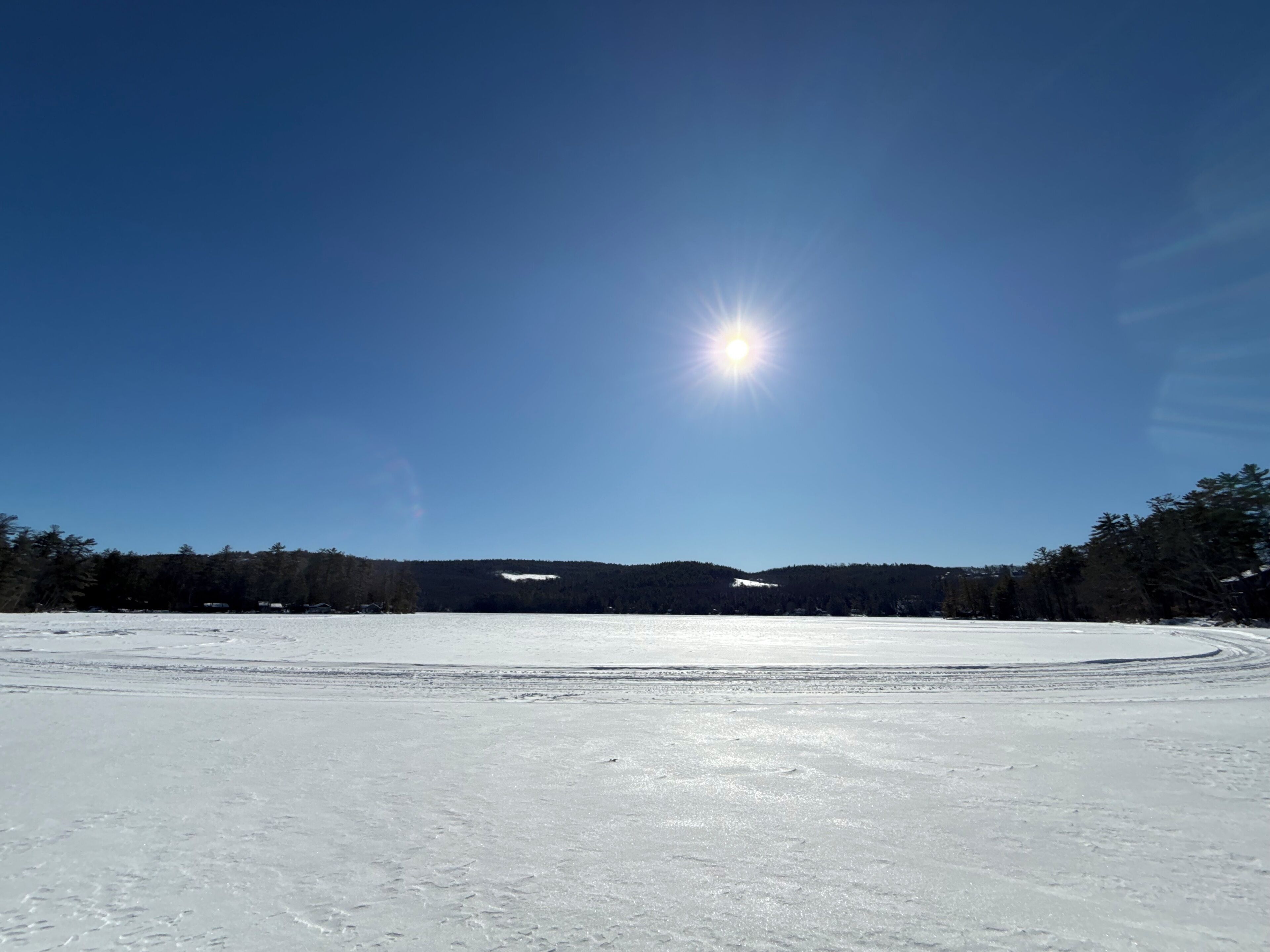 A snow-covered landscape with a clear sky and a bright sun.