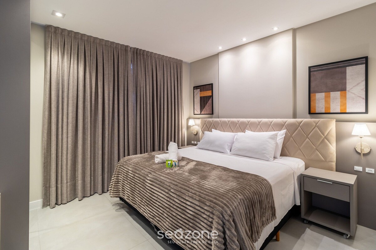 Een moderne hotelkamer met een groot bed, een nachtkastje, een wandlamp en een ingelijste foto.