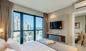 Camera d'albergo con una grande finestra, una TV a schermo piatto, un letto, una scrivania e una sedia.
