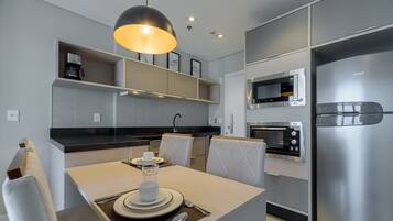 A modern kitchen with built-in appliances, a dining area with a table set for two, and a pendant light above.