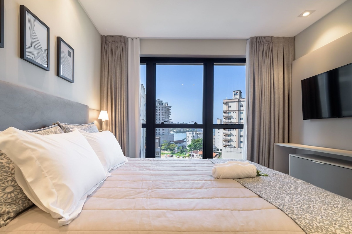 Una habitación de hotel con cama, televisión y vista a la ciudad.