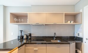 Una cocina moderna con encimera negra, electrodomésticos de acero inoxidable y horno empotrado.