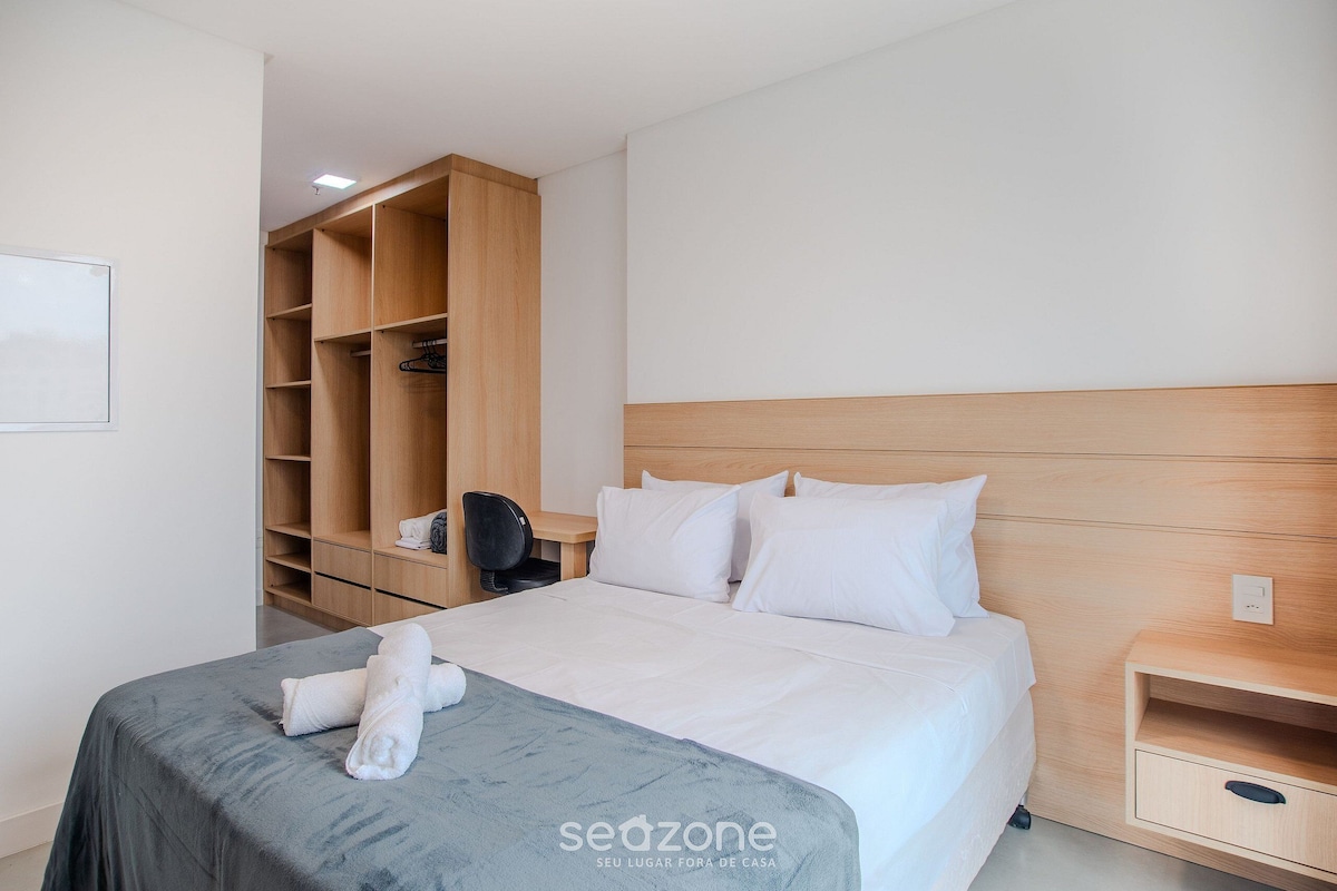 Une chambre d’hôtel avec un lit, une armoire en bois, un bureau et une table de chevet.
