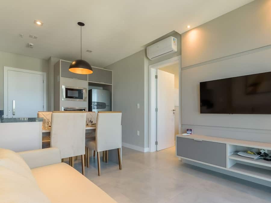 Una sala moderna con sofá, comedor, cocina y televisor montado.