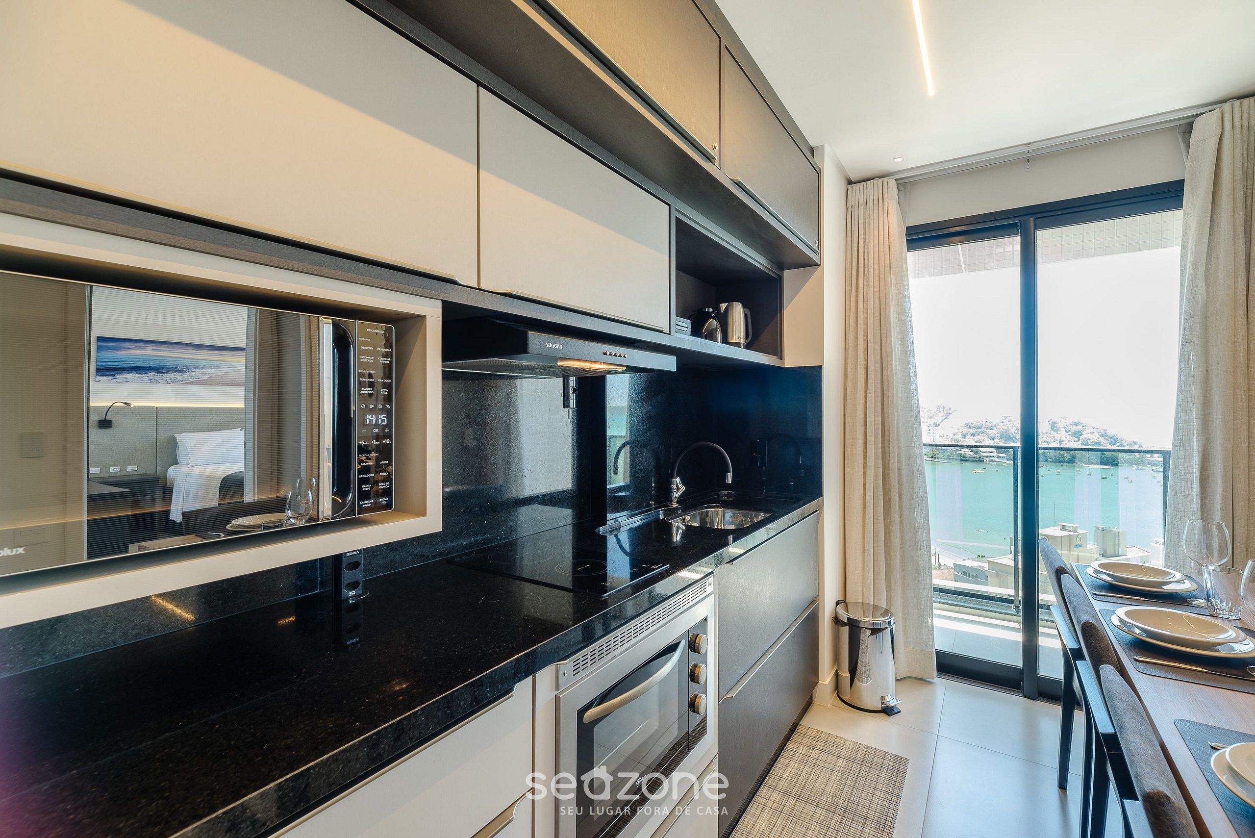 A modern kitchen with a built-in microwave, oven, and sink. There is a dining area with a table set for four.