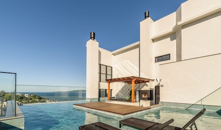 A rooftop infinity pool with a wooden deck, a pergola, and a view of the sea.. MHFs Apartamentos com Vista Mar Itapema
