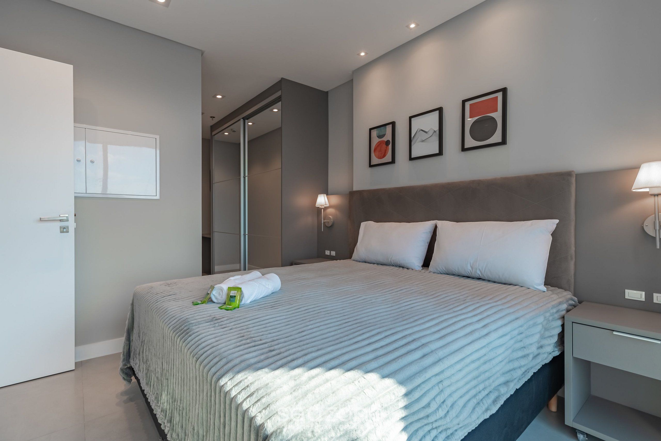 Une chambre d’hôtel moderne avec un grand lit, une table de chevet, une armoire et une porte.