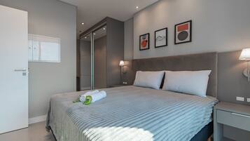 Une chambre d’hôtel moderne avec un grand lit, une table de chevet, une armoire et une porte.