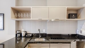 A modern kitchen with a built-in stove, a sink, and a coffee maker. - MHFs Apartamentos com Vista Mar Itapema (Itapema)