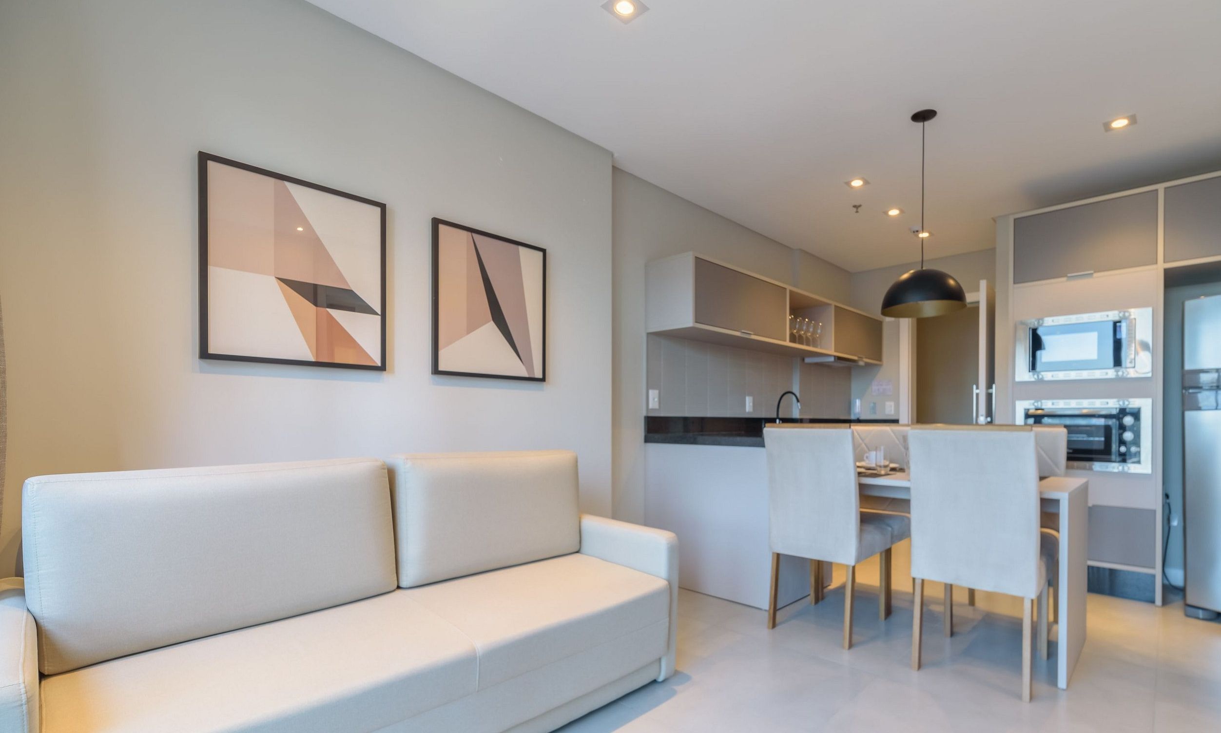 A modern living room with a sofa and chairs, a dining area with a table, and a kitchen with appliances.