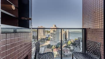 A balcony with two chairs, a view of a cityscape, and a tiled wall.