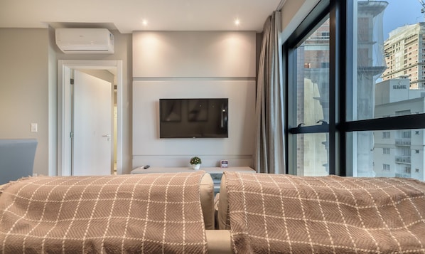 Een hotelkamer met een bed, een televisie, een raam en een deur.