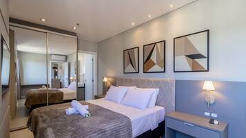 A hotel room with a bed, bedside tables, a mirror, and artwork on the wall.