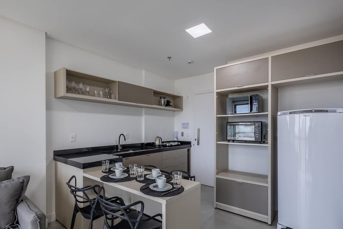 A compact kitchen with a countertop, chairs, and a built-in microwave and refrigerator.