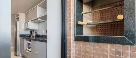 Une cuisine moderne équipée d’un four encastré, d’une machine à café et d’un réfrigérateur en acier inoxydable.