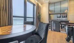 Une cuisine moderne avec vue sur la mer, un coin repas avec une table et des chaises, et un bar avec des verres.